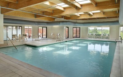 Relaxing indoor pool with lounge chairs at Courtyard By Marriott Toronto Airport.