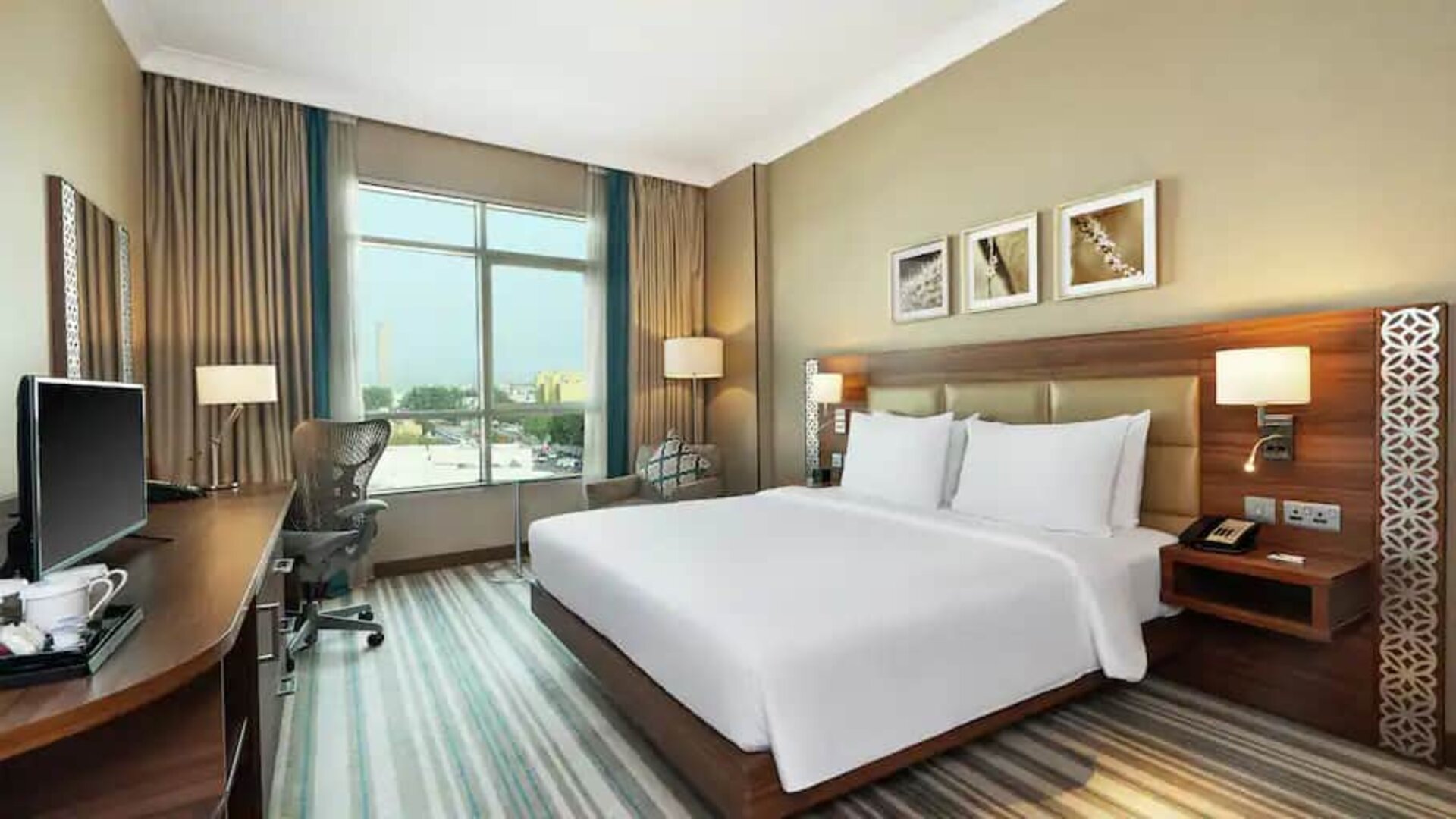 Comfortable King room with king bed, desk, tv and living room area at the Hilton Garden Inn Dubai Al Mina