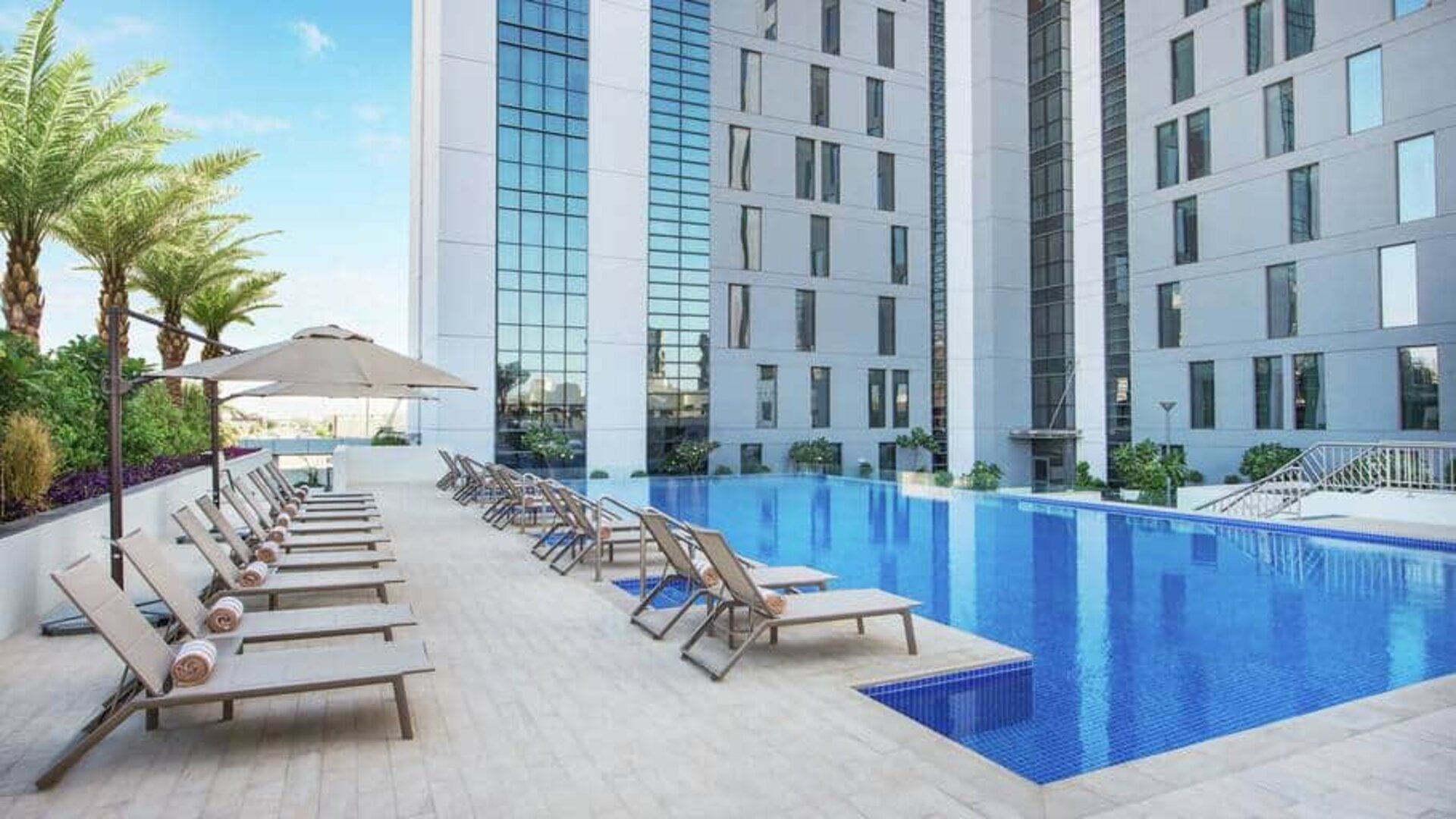 Beautiful outdoor pool with pool chairs at the Hampton Dubai Airport