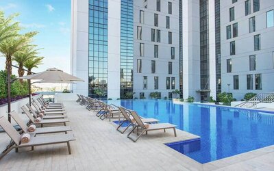 Beautiful outdoor pool with pool chairs at the Hampton Dubai Airport