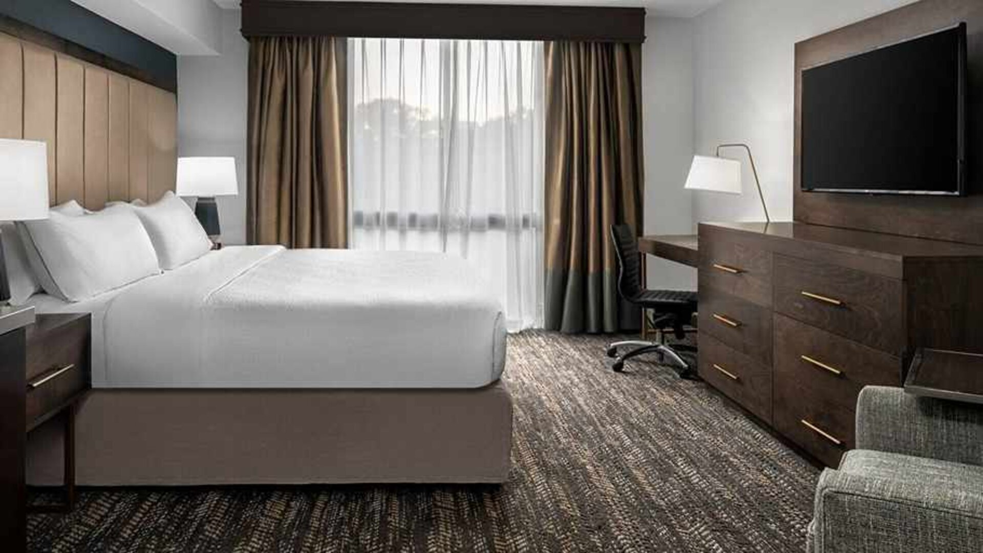 Comfortable king bed with TV and work area at Embassy Suites by Hilton Nashville Airport.