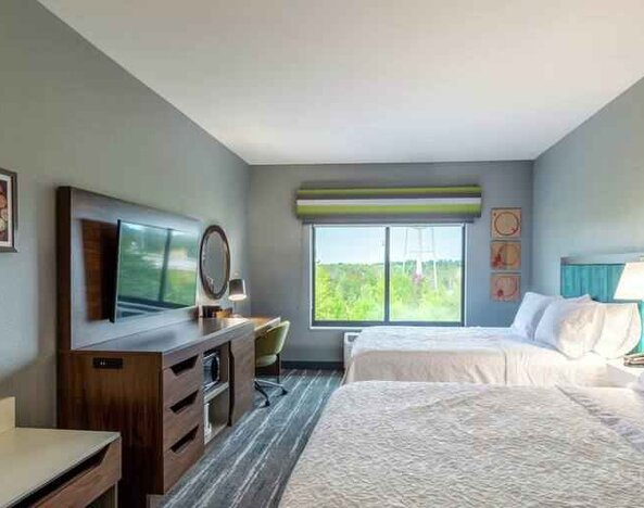 Double queen bedroom with desk, window and TV screen at the at the Hampton Inn Madison, OH.