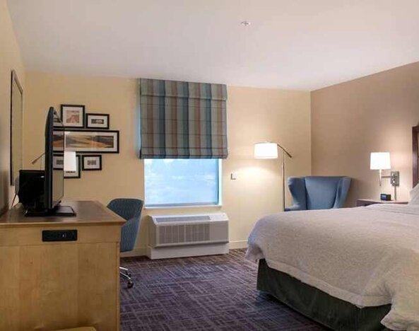 Comfortable king-sized bed with work area at Hampton Inn Big Rapids, MI.