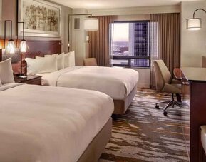 Stylish bedroom with two queen size beds, desk and TV screen at the Hilton Denver City Center.