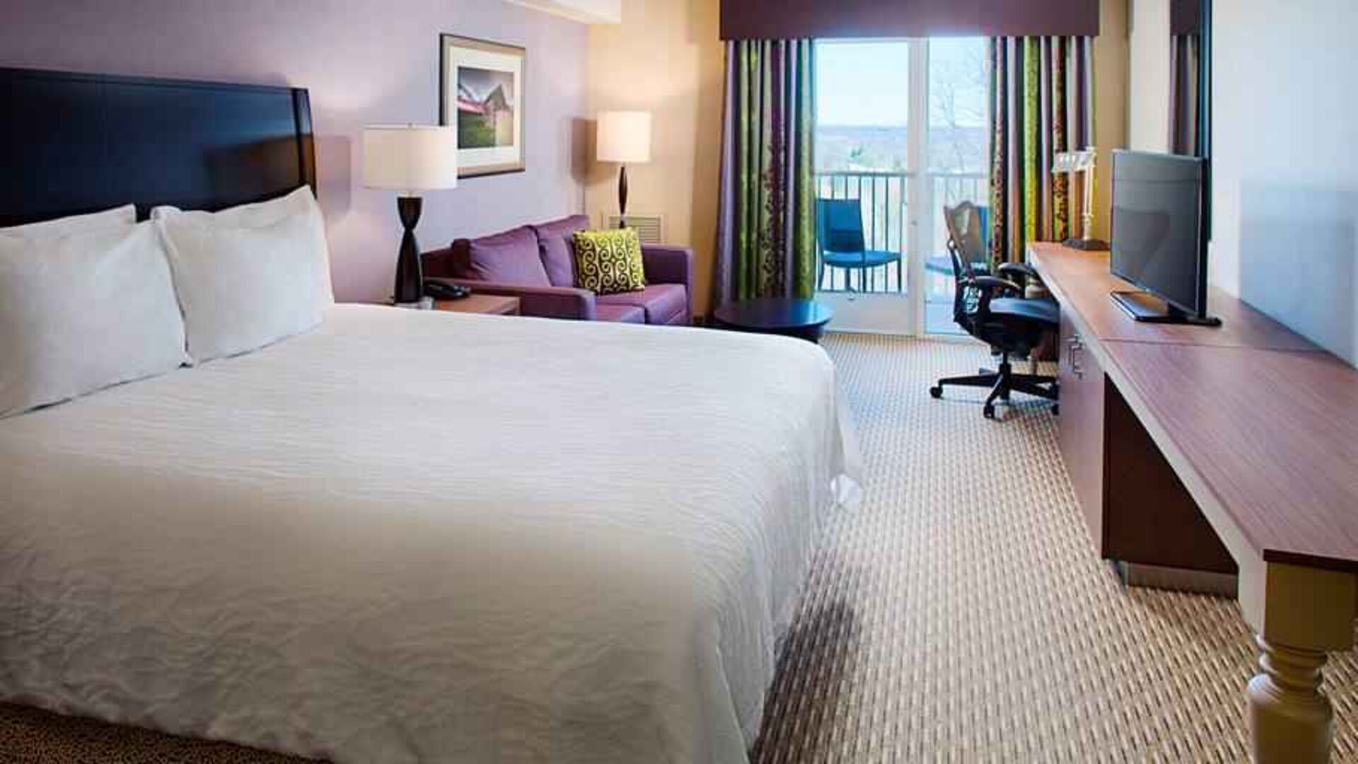 Comfortable king size bed, sofa and desk in a hotel room at the Hilton Garden Inn Hartford North/Bradley Intl Airport.