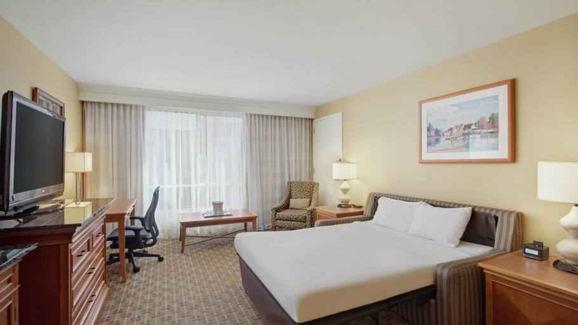 King size bed, desk and TV screen in a hotel room at the Hilton Seattle Airport & Conference Center.