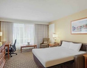 King size bed, desk and TV screen in a hotel room at the Hilton Seattle Airport & Conference Center.