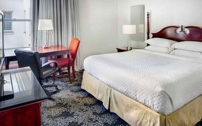 King size bed, desk and TV screen in a hotel room at the Embassy Suites by Hilton Portland-Downtown.