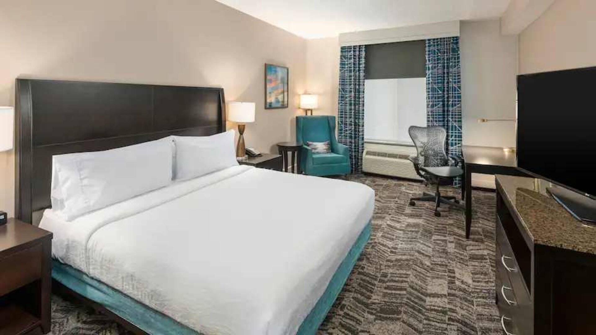 Comfortable hotel guestroom with king size bed and working station at the Hilton Garden Inn Silver Spring White Oak.