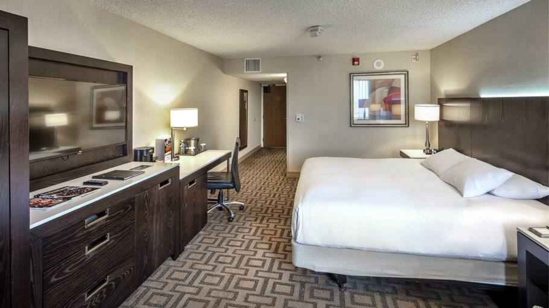 TV screen, desk and sofa in a king suite at the Hilton Sacramento-Arden West.
