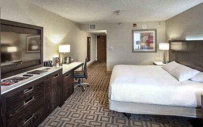 TV screen, desk and sofa in a king suite at the Hilton Sacramento-Arden West.