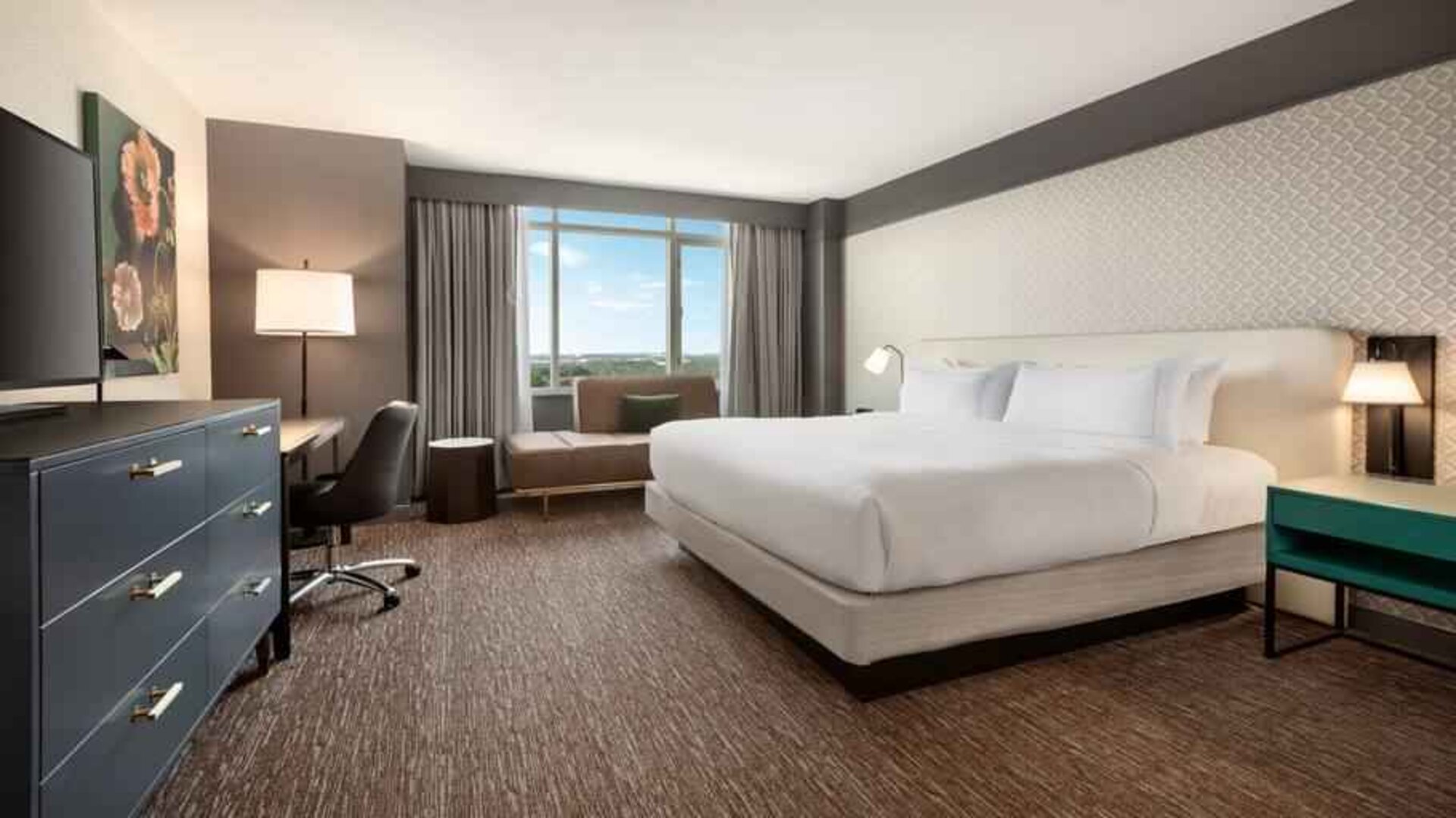 King guestroom with TV screen, desk and window at the Hilton Baltimore BWI Airport.