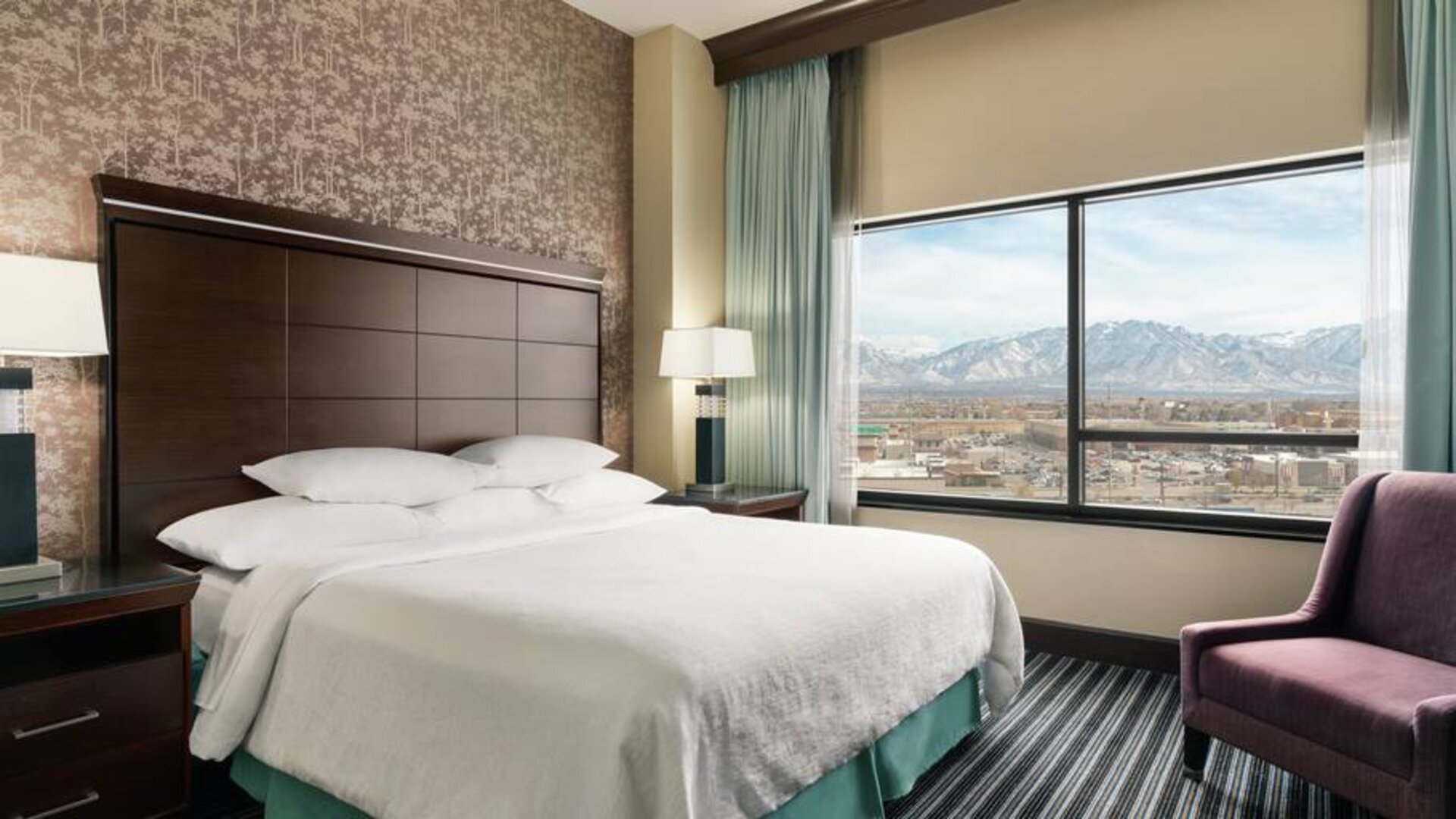 Bright king bedroom with large window at the Embassy Suites by Hilton Salt Lake City West Valley.
