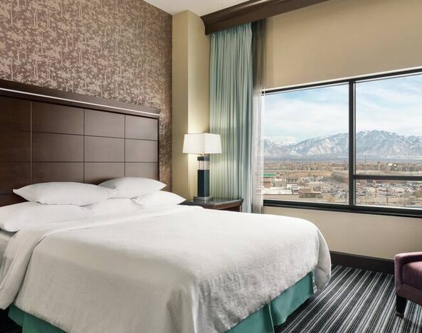 Bright king bedroom with large window at the Embassy Suites by Hilton Salt Lake City West Valley.