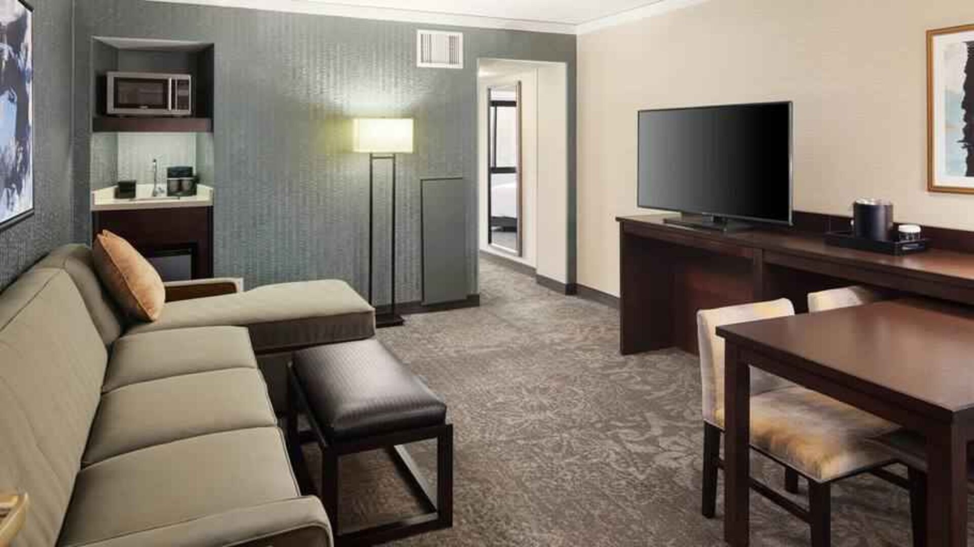 Spacious and comfortable hotel living room with sofa and desk at the Embassy Suites by Hilton Tysons Corner.