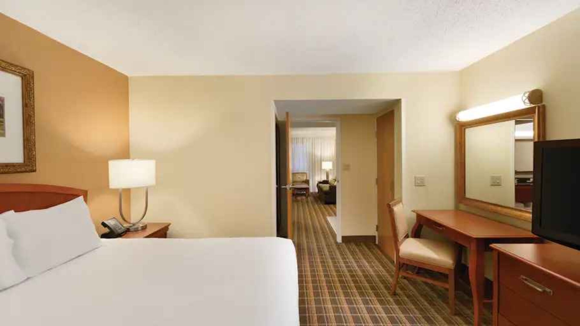 King suite with TV screen and desk at the Embassy Suites by Hilton Greenville Golf Resort Conference Center