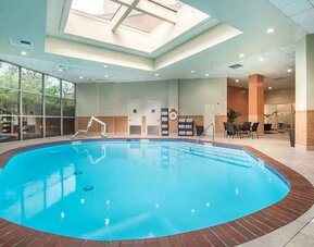 Bright-lit indoor pool with sun roof and comfortable seating area at Embassy Suites by Hilton Seattle Tacoma International Airport.