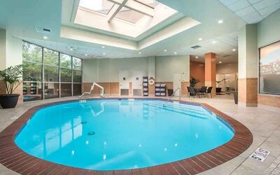 Bright-lit indoor pool with sun roof and comfortable seating area at Embassy Suites by Hilton Seattle Tacoma International Airport.