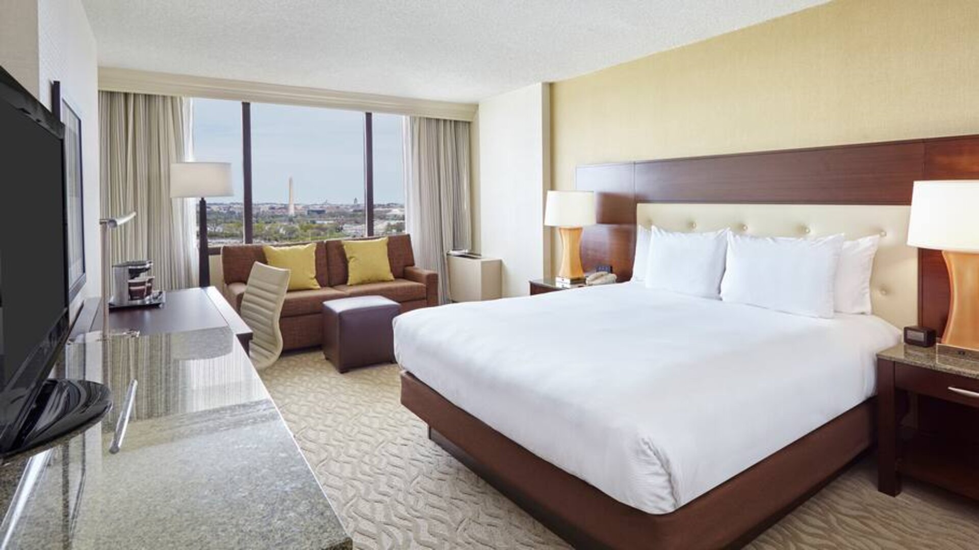 Bright king bedroom with sofa, window and desk at the DoubleTree by Hilton Washington DC - Crystal City.