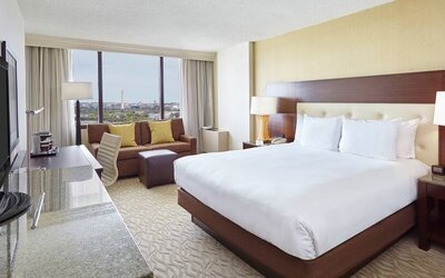 Bright king bedroom with sofa, window and desk at the DoubleTree by Hilton Washington DC - Crystal City.
