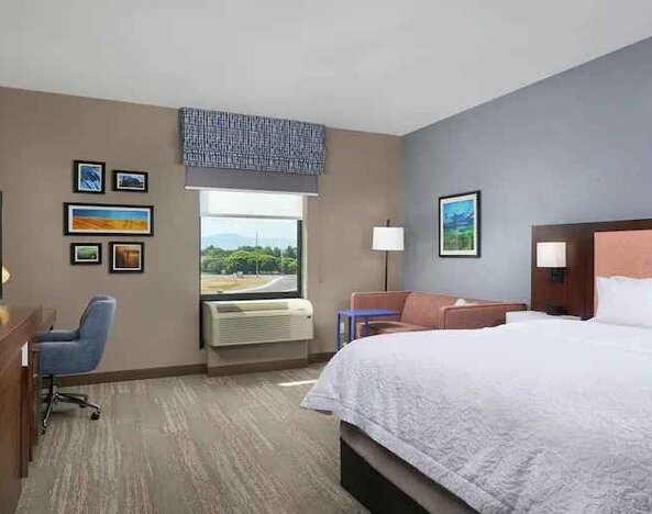 King bedroom with desk, window and sofa at the Hampton Inn Burley.