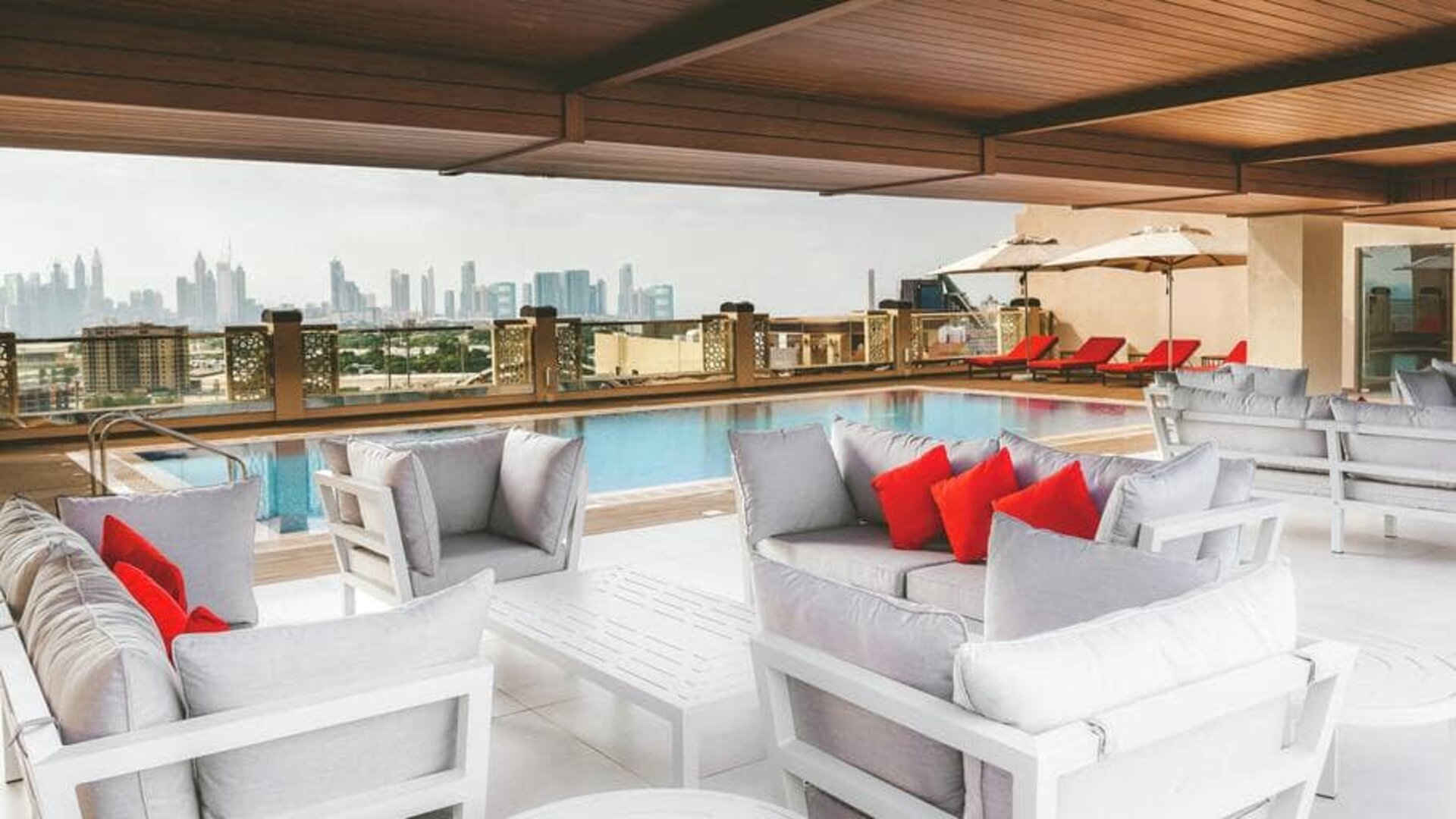Rooftop pool with seating overlooking a city view at the Hilton Dubai Al Jadaf.