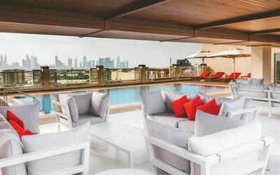Rooftop pool with seating overlooking a city view at the Hilton Dubai Al Jadaf.