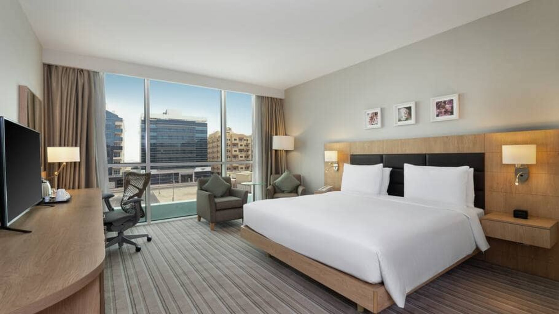 King-sized bed with view of city buildings at the Hilton Garden Inn Dubai Mall of the Emirates.