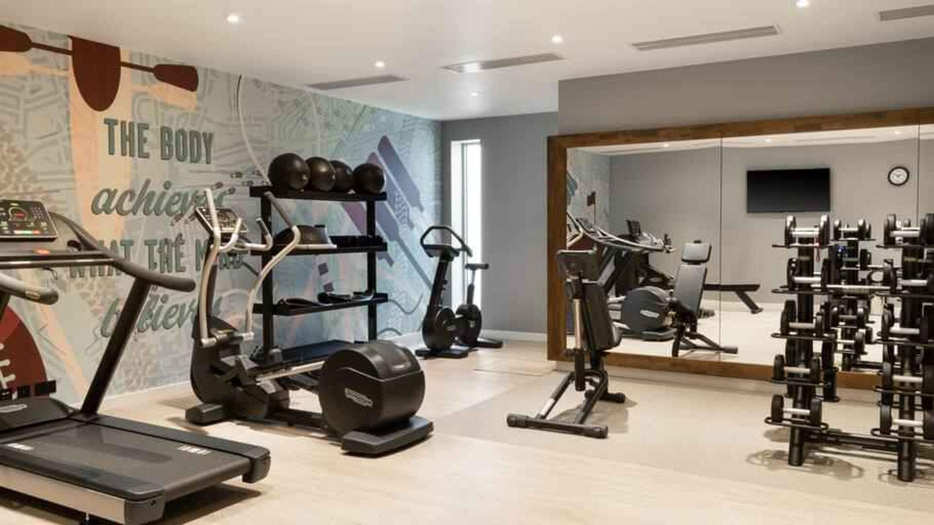 Fitness center with weights and machines at the Hampton by Hilton London Ealing.