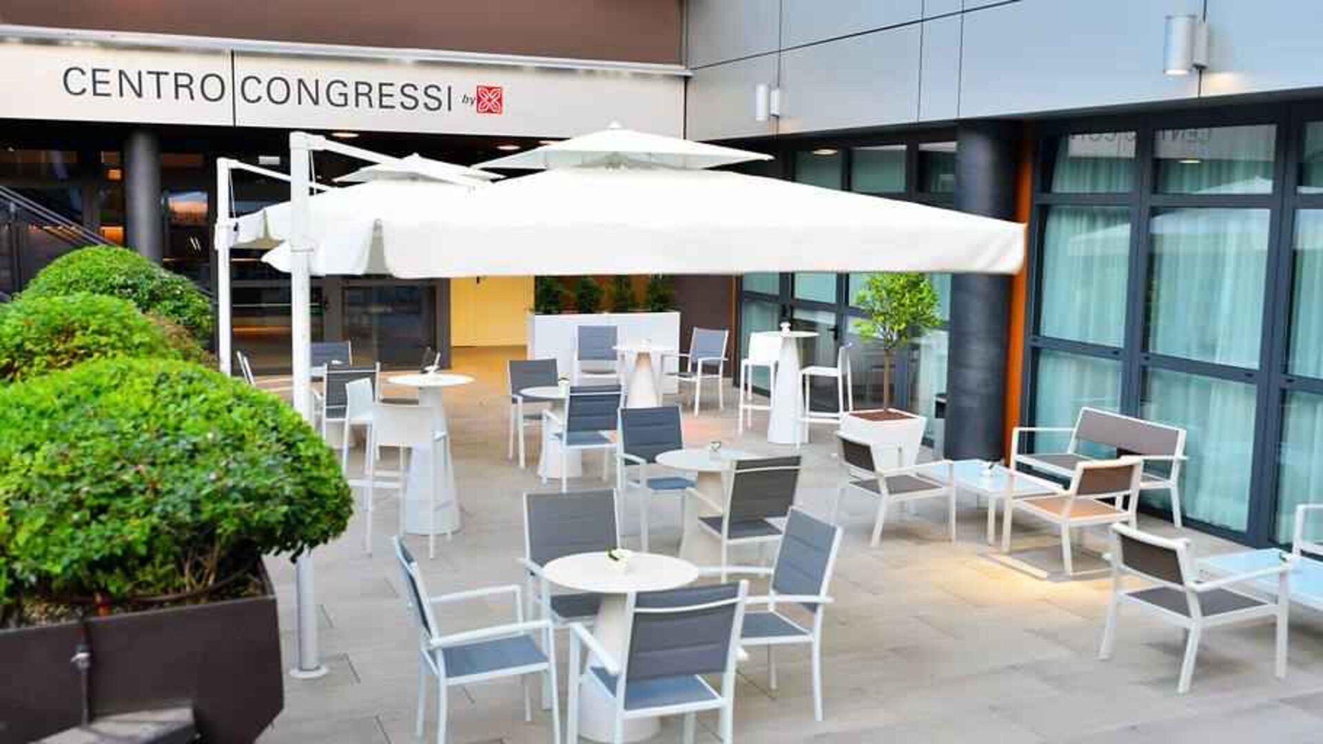 Outdoor terrace with sun umbrellas, chairs and tables at the Hilton Garden Inn Milan North.