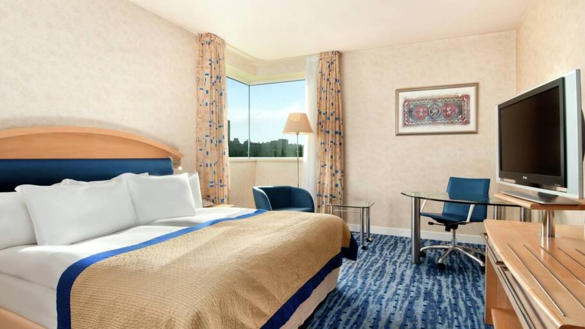 Bright, spacious king guest suite with television, king bed and work space at the HIlton Sofia, in Bulgaria.