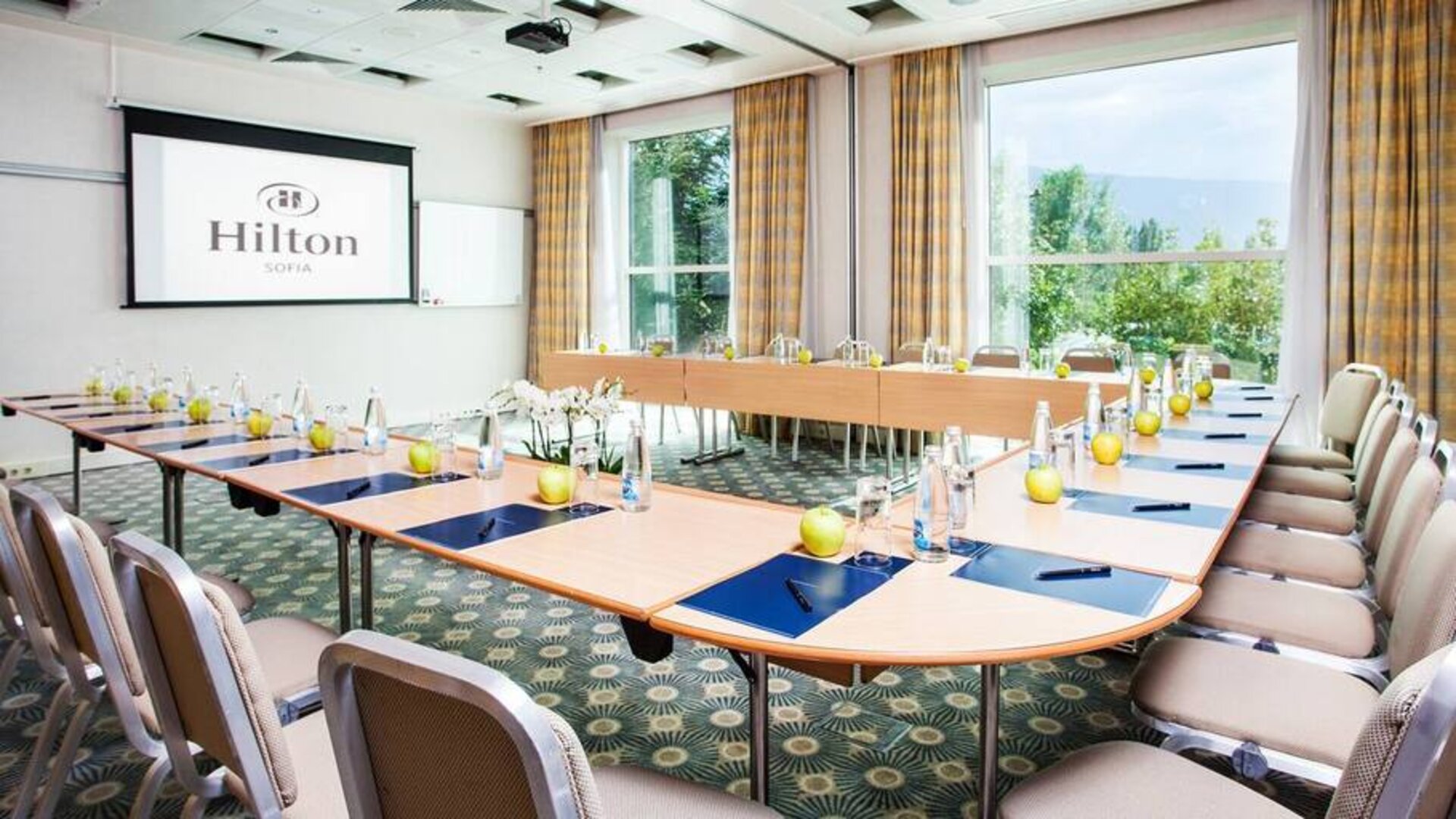 Wide u-shaped area for seating for 20-30 guests, large projection screen in center and windows all around.