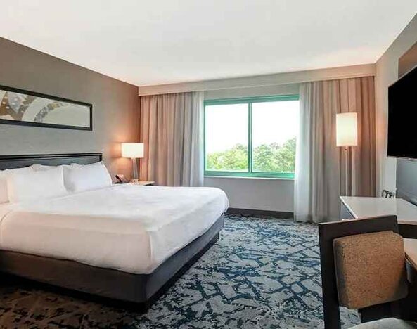 spacious king room with TV and work desk at Embassy Suites by Hilton Raleigh Durham Research Triangle.