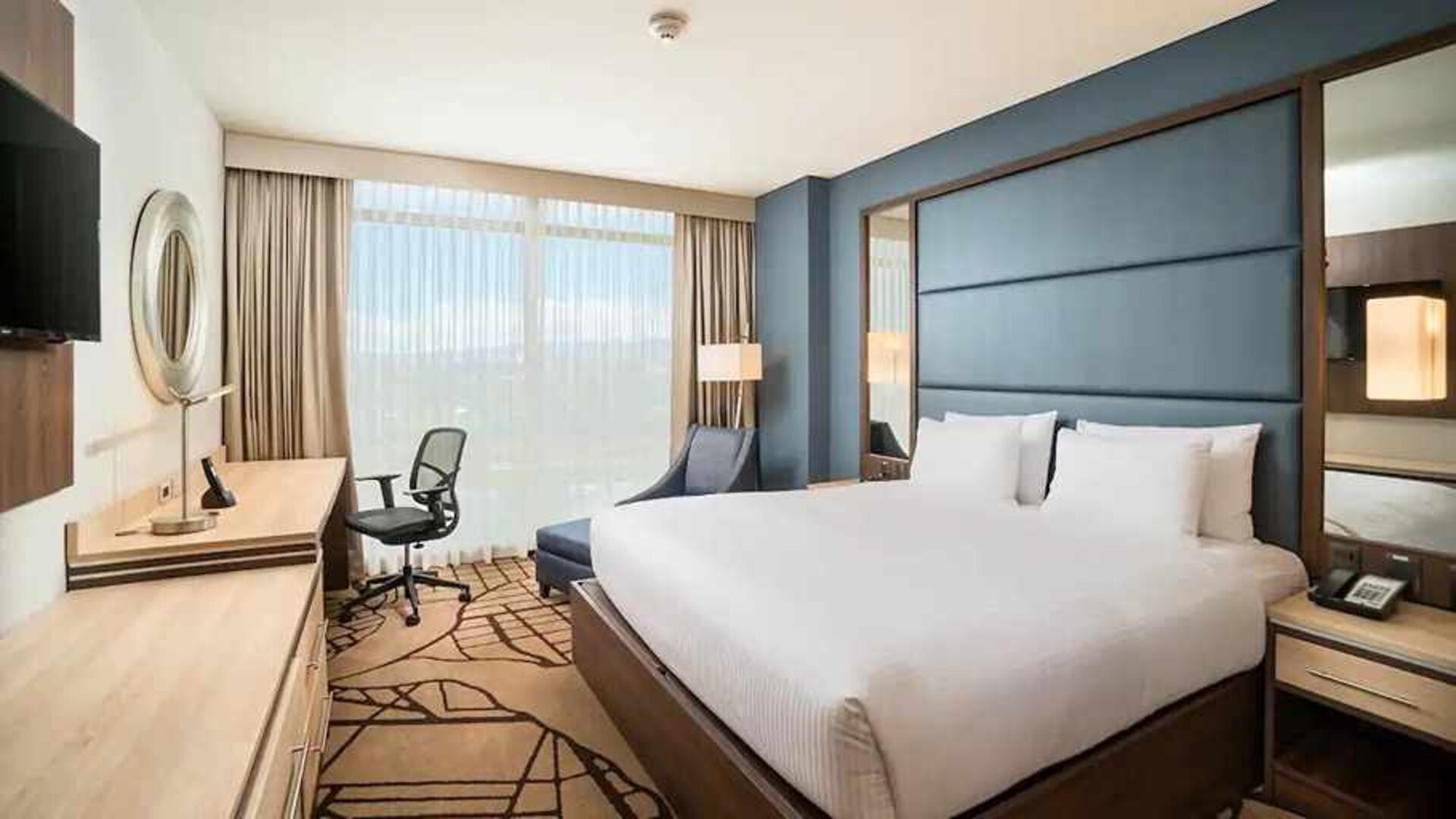 comfortable king room with TV, work desk, and natural light at Hilton Garden Inn Bogota Airport.