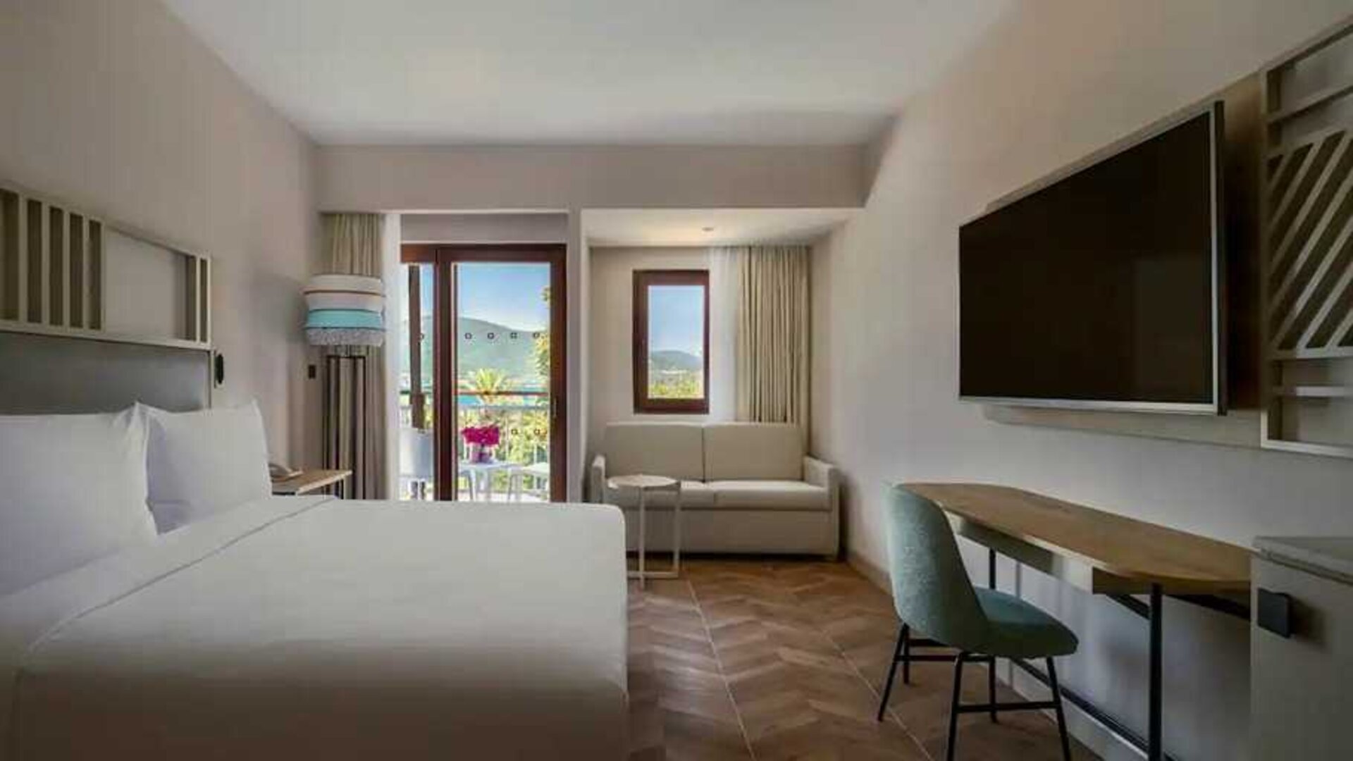 spacious king room with lots of natural light, sea view, TV, and work desk at DoubleTree by Hilton Bodrum Isil Club Resort.