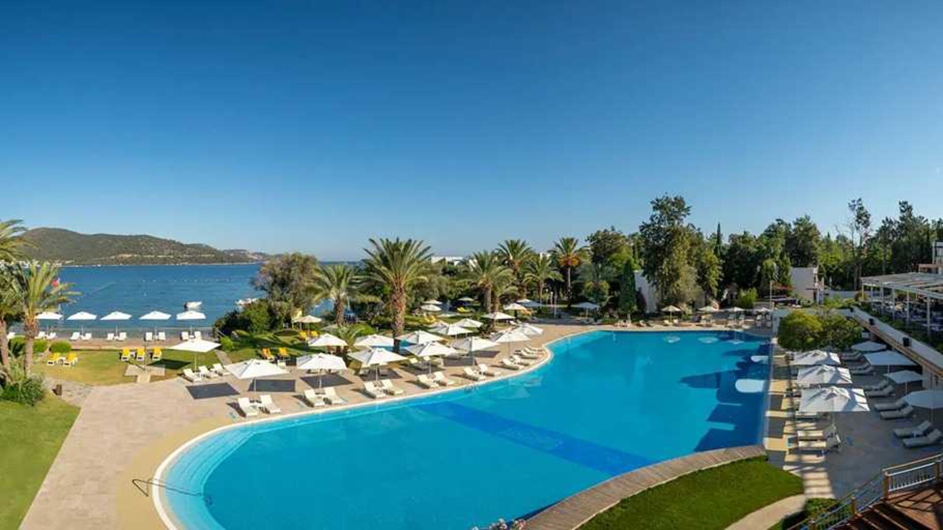stunning outdoor pool surrounded by sun beds and pool umbrellas at DoubleTree by Hilton Bodrum Isil Club Resort.