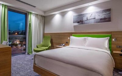 comfortable king bed with work desk and large windows at Hampton by Hilton Istanbul Zeytinburnu.