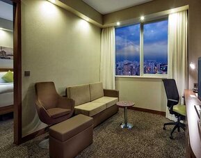 spacious king suite with TV, work desk and chair, lounge area, and coffee station at Hampton by Hilton Istanbul Kayasehir.