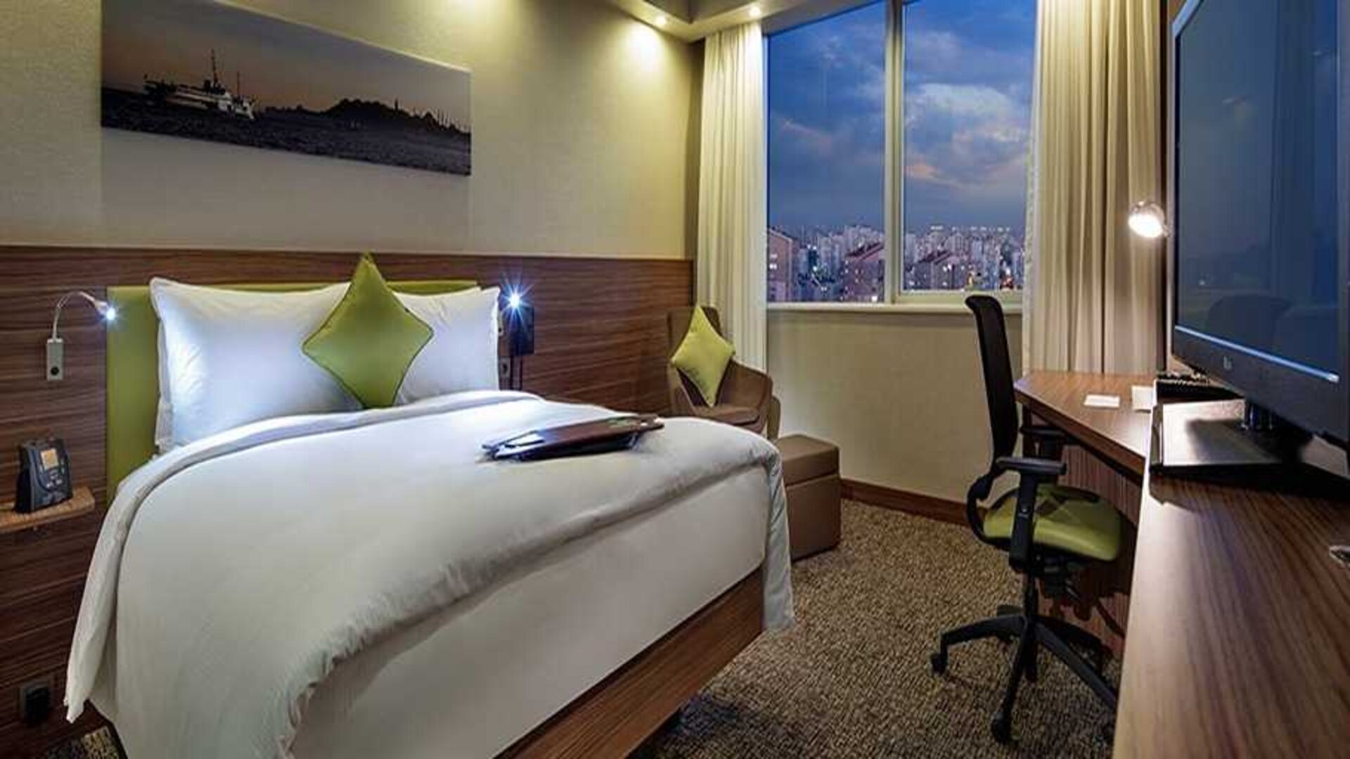 comfortable king bedroom with TV, desk, and chair at Hampton by Hilton Istanbul Kayasehir.