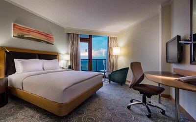 spacious king room with TV, desk, chair, and lots of natural light at Mersin HiltonSA.