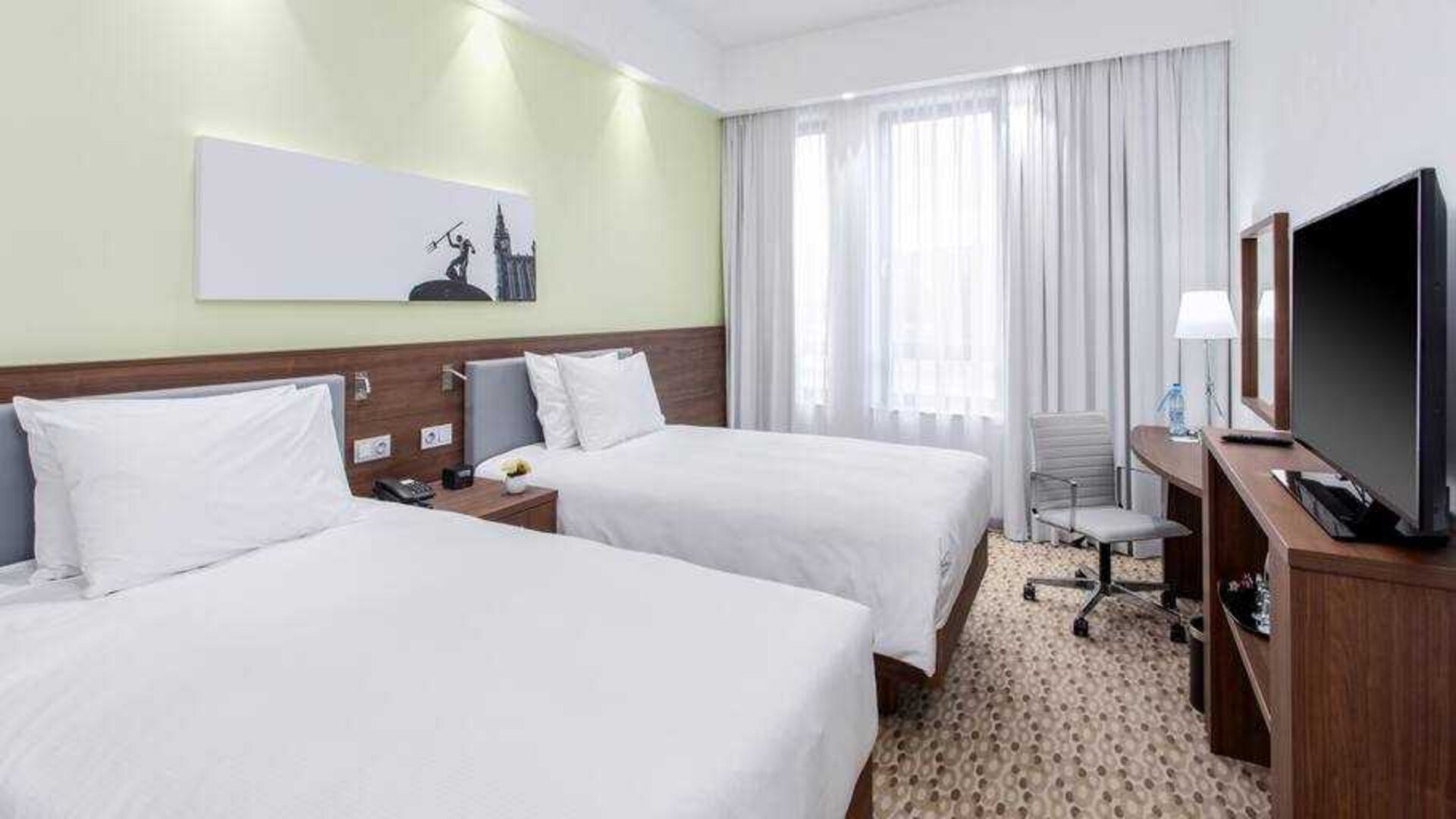 Twin room with TV screen and working station at the Hampton by Hilton Gdansk Oliwa.