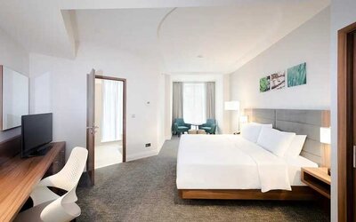 spacious king room with TV, desk, chair, and lots of natural light at Hilton Garden Inn Bucharest Old Town.