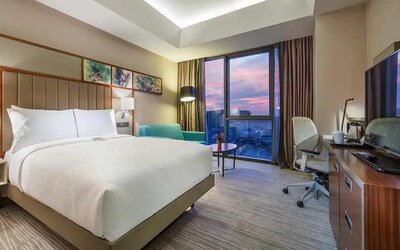 standard king room with TV, work desk, chair, and couch at Hilton Garden Inn Istanbul Ataturk Airport.