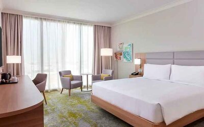 spacious king room with TV, business desk, chair, and couch at Hilton Garden Inn Kuwait.