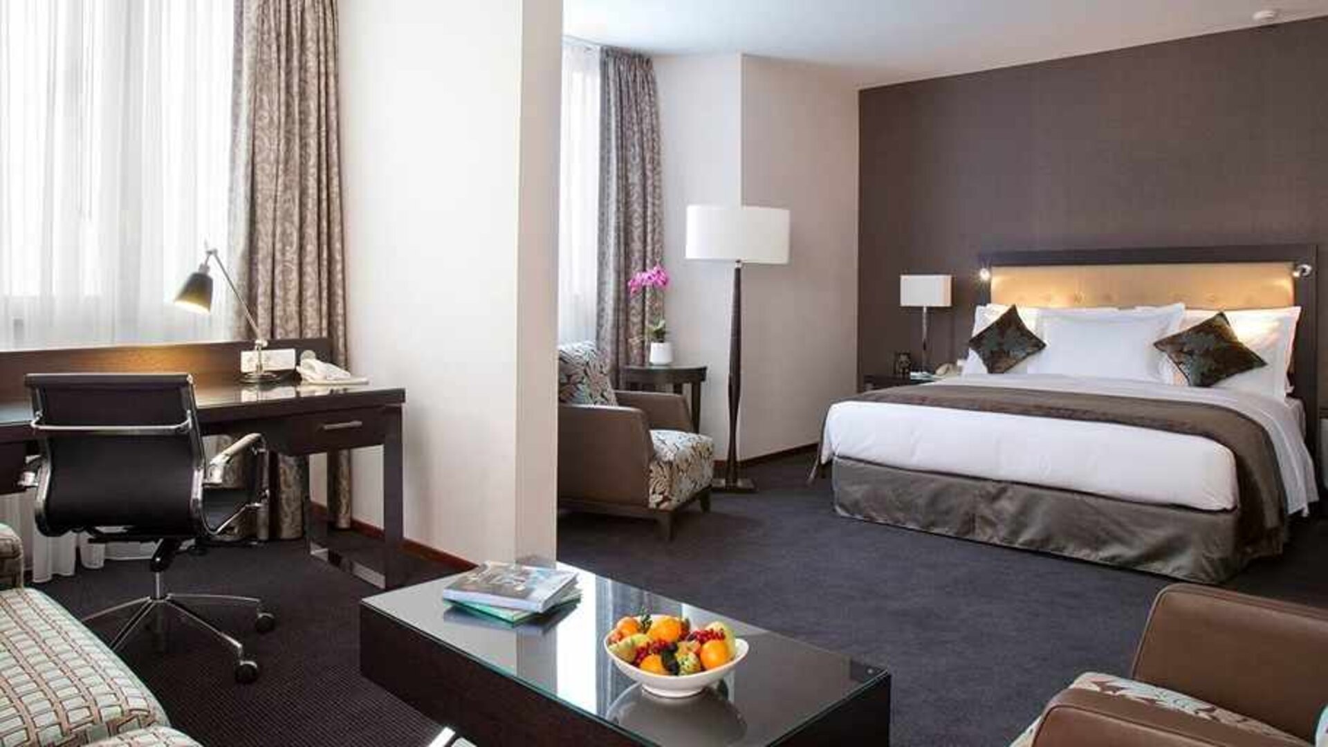 spacious king room with TV, work desk, chair, and couch at DoubleTree by Hilton Luxembourg.