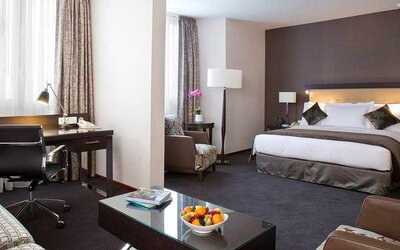 spacious king room with TV, work desk, chair, and couch at DoubleTree by Hilton Luxembourg.