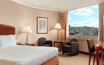 comfortable king room with TV, desk, chair, and couches at Hilton Colon Quito.