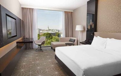spacious king room with TV, desk, chair, and couch at Hilton Tallinn Park.