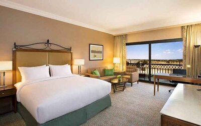 spacious delux king bedroom with TV, desk, chair, and lounge area at Hilton Alexandria King's Ranch.