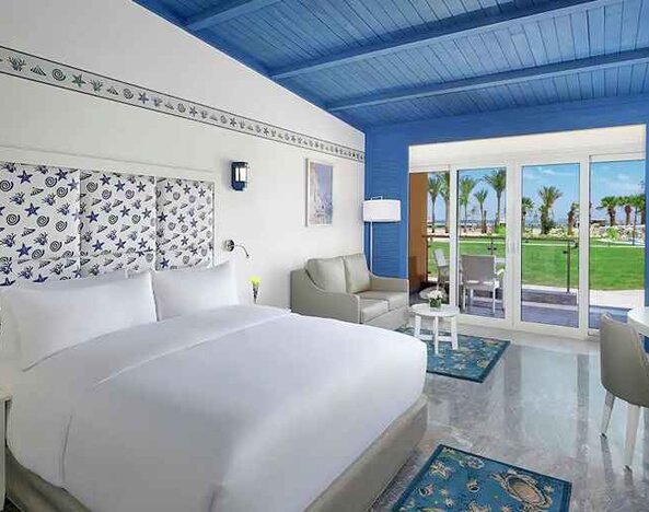 spacious king suite with desk, chair, couch, and outdoor terrace at Hilton Hurghada Plaza.